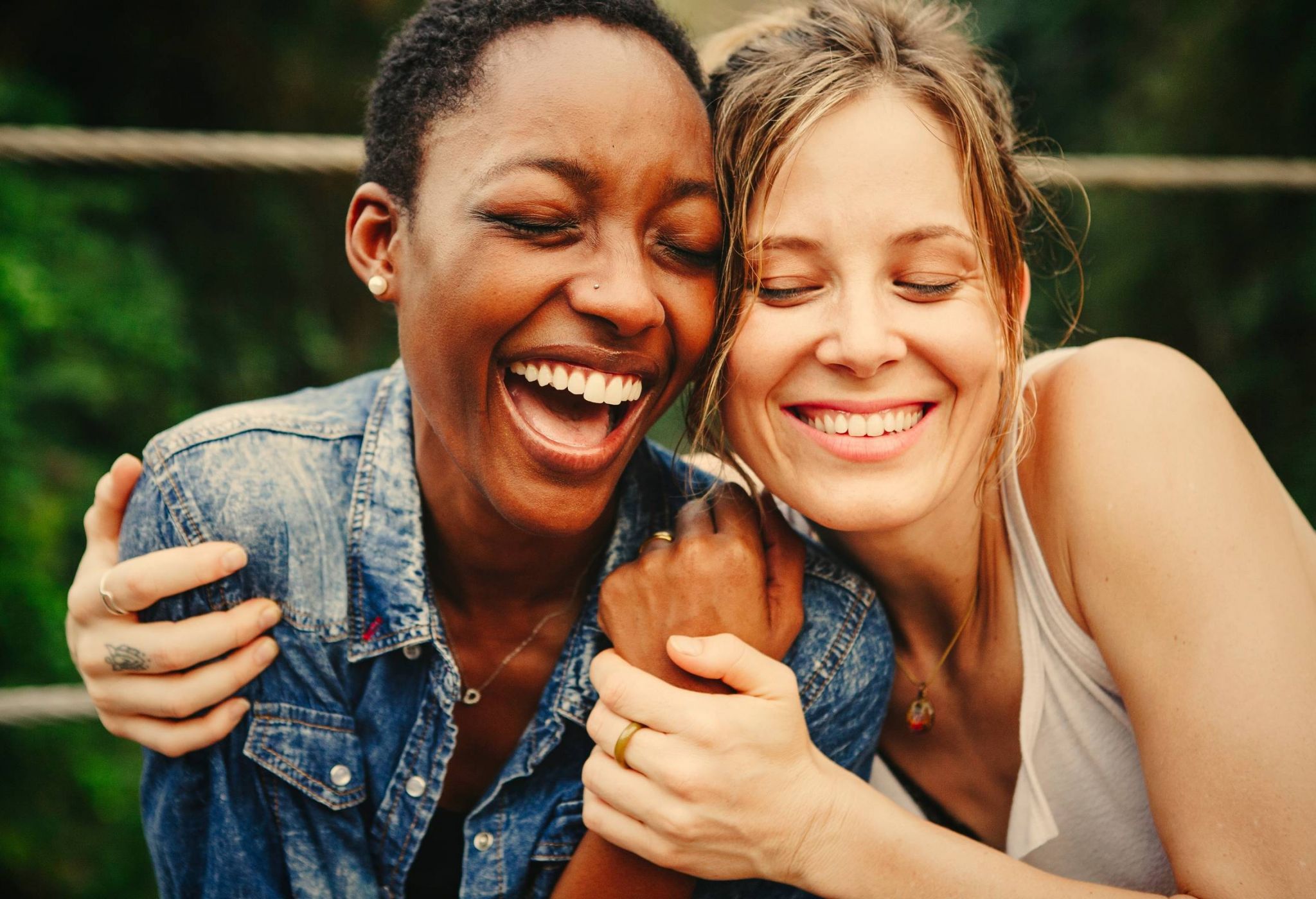 Two people smiling and laughing while embracing each other outdoors.