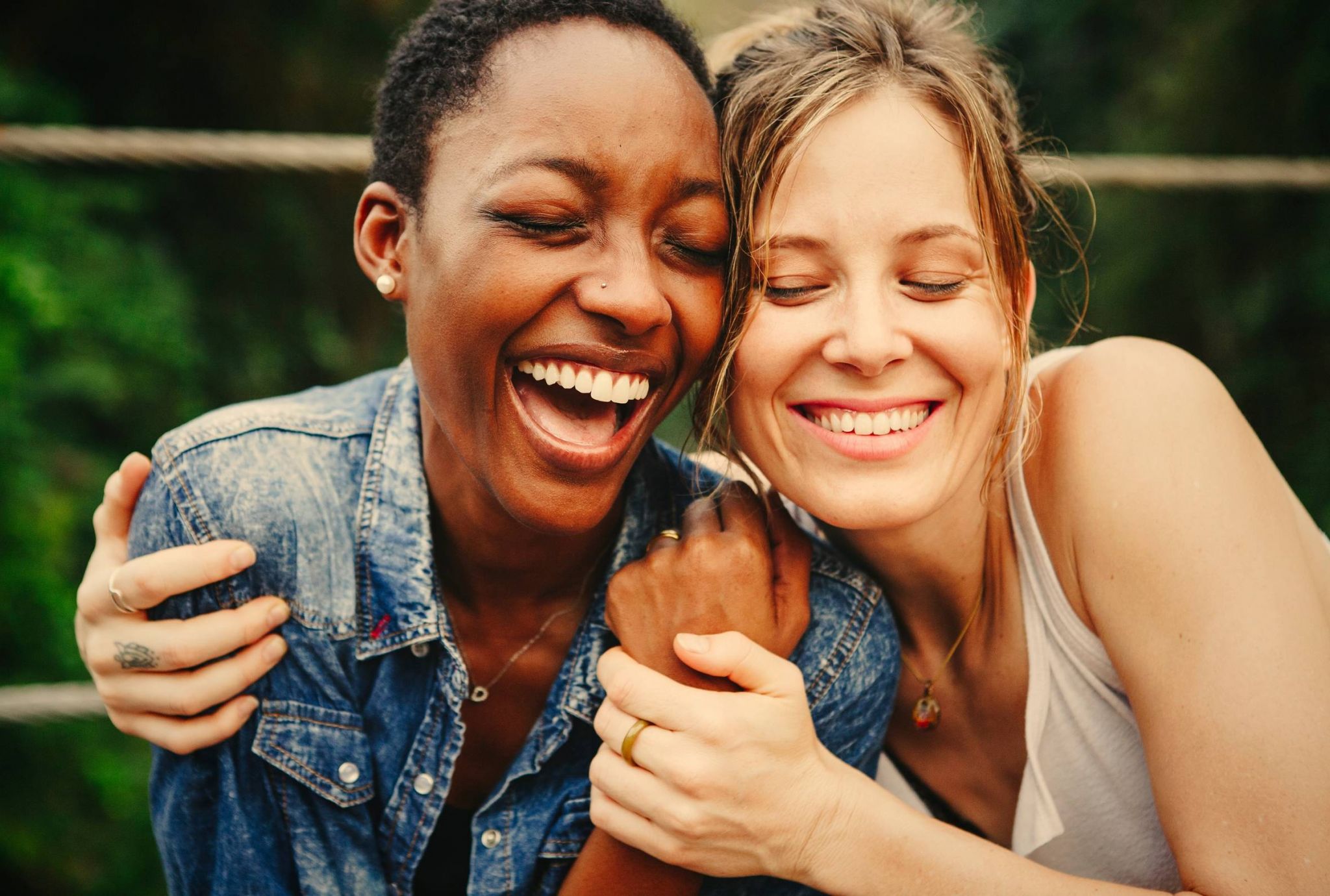 Two people smiling and laughing while embracing each other outdoors.