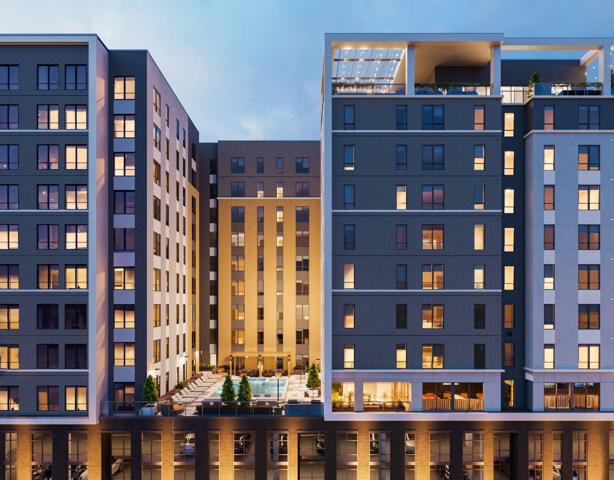 EVER Knoxville apartments Modern multi-story apartment building at dusk, with illuminated windows and a central outdoor pool area.