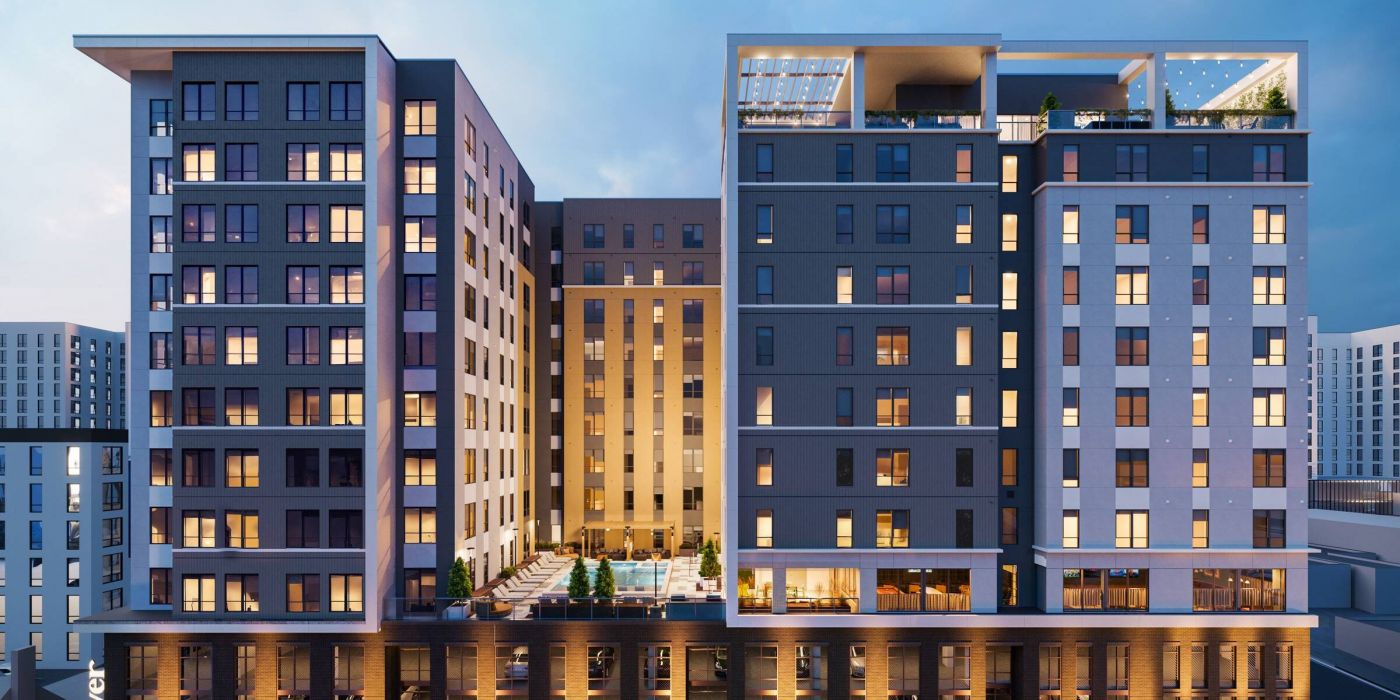 EVER Knoxville apartments Modern multi-story apartment building at dusk, with illuminated windows and a central outdoor pool area.