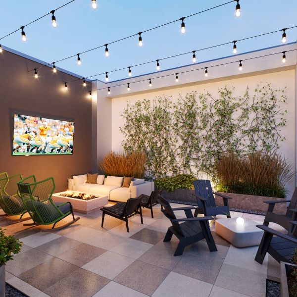 EVER Knoxville apartments Outdoor patio with dining tables, grill, foosball table, TV, and string lights under a slatted pergola.
