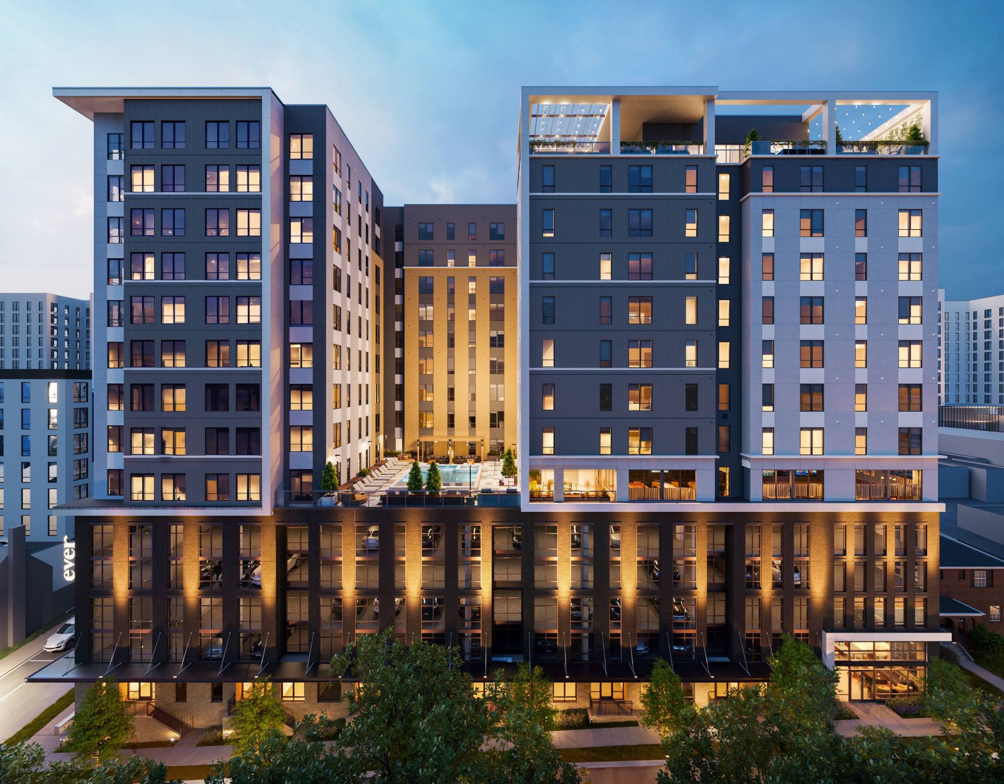 EVER Knoxville apartments Modern multi-story apartment building at dusk, with illuminated windows and a central outdoor pool area.