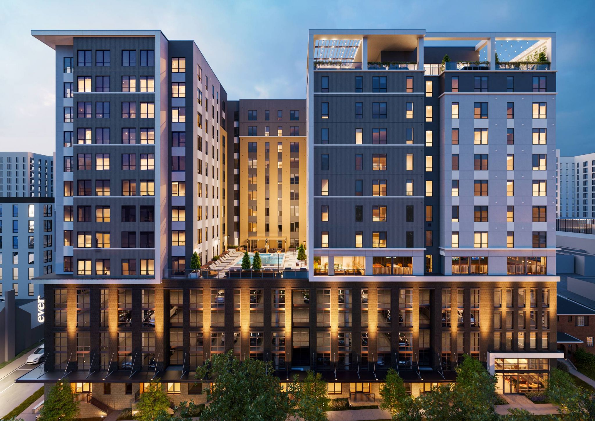 EVER Knoxville apartments Modern multi-story apartment building at dusk, with illuminated windows and a central outdoor pool area.