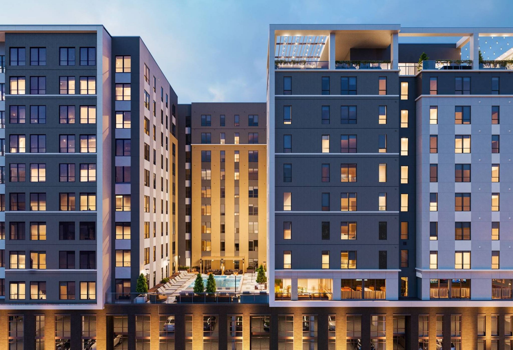 EVER Knoxville apartments Modern multi-story apartment building at dusk, with illuminated windows and a central outdoor pool area.