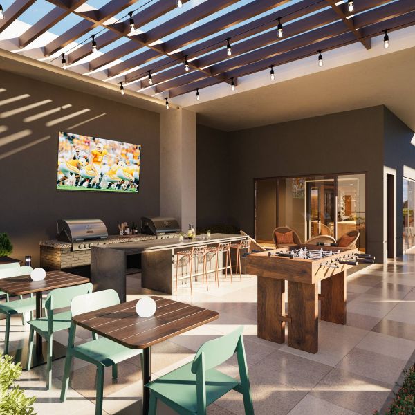 EVER Knoxville apartments Outdoor patio with dining tables, grill, foosball table, TV, and string lights under a slatted pergola.