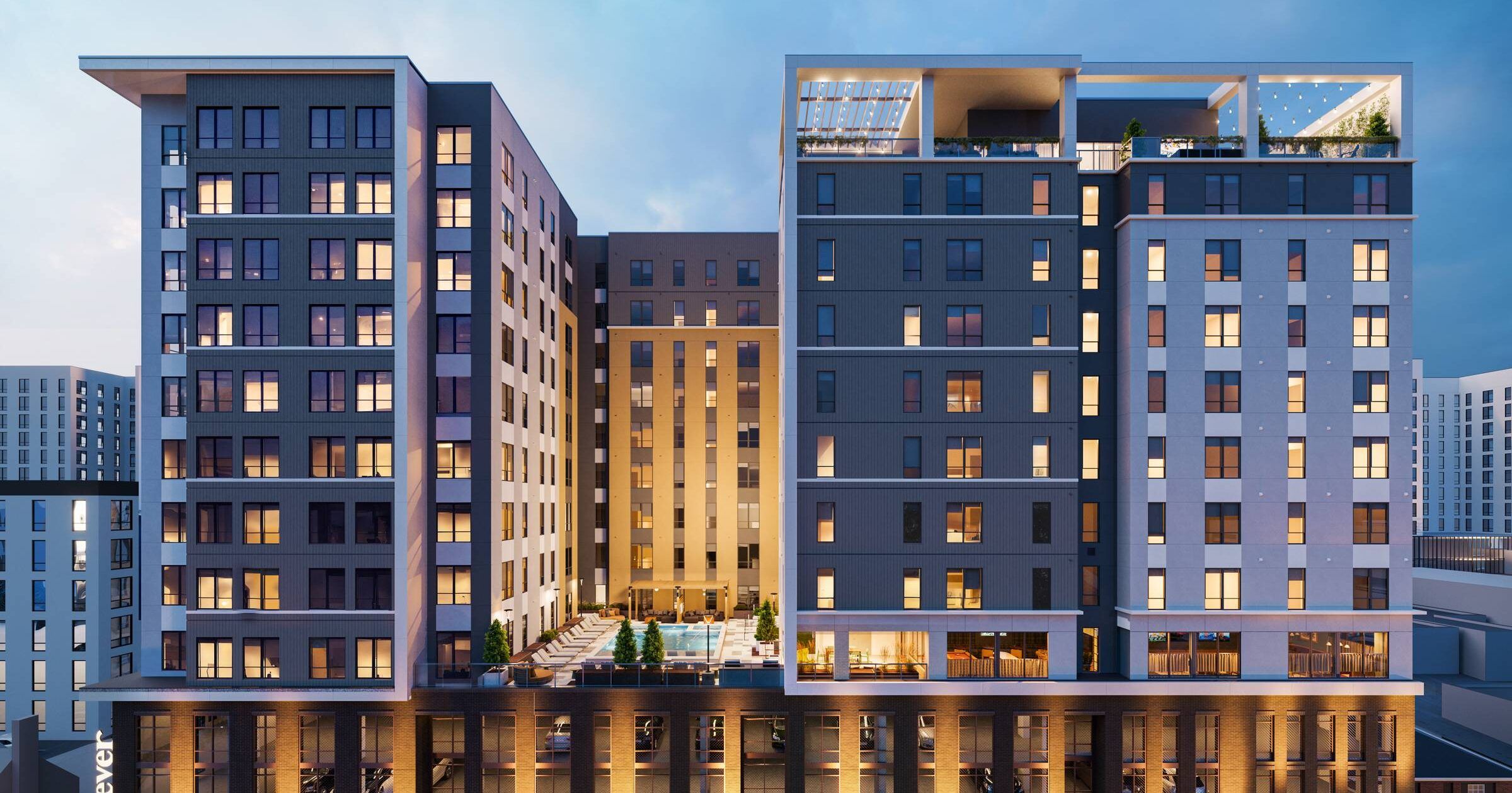 EVER Knoxville apartments Modern multi-story apartment building at dusk, with illuminated windows and a central outdoor pool area.