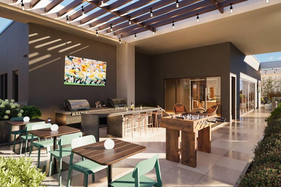 EVER Knoxville apartments Outdoor patio with dining tables, grill, foosball table, TV, and string lights under a slatted pergola.