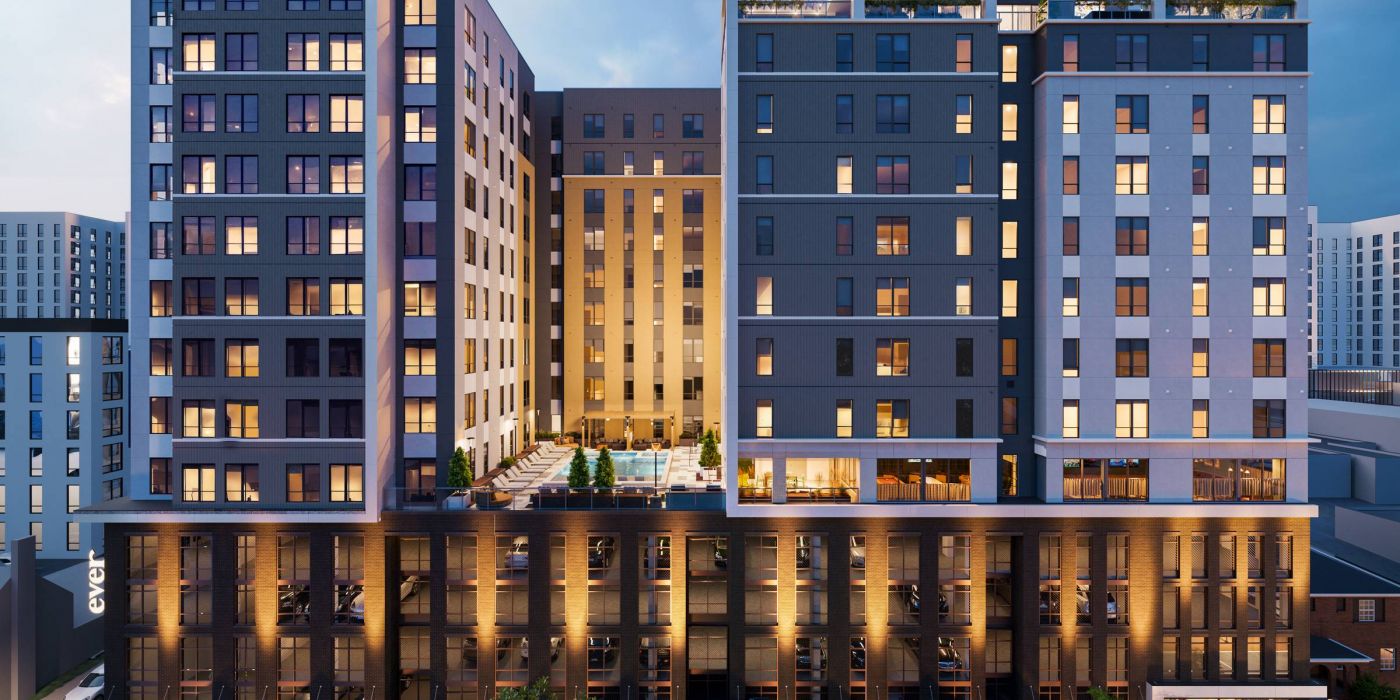 EVER Knoxville apartments Modern multi-story apartment building at dusk, with illuminated windows and a central outdoor pool area.